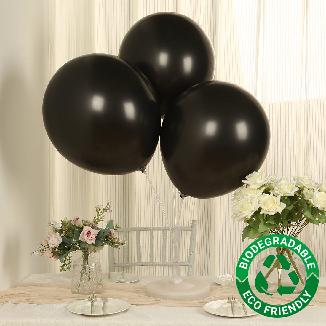 Black biodegradable balloons on a table with flowers and a green eco-friendly label.