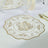 Elegant gold floral design paper plate on a dining table setting.