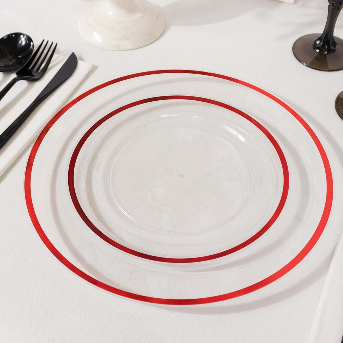Clear plate with red rim design on a table setting.