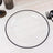 Clear plate with a black rim on a white wooden table.