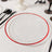 Clear plate with red rim on a stylish dining table setting.