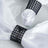 Elegant white napkins with black beaded rings on a plate.
