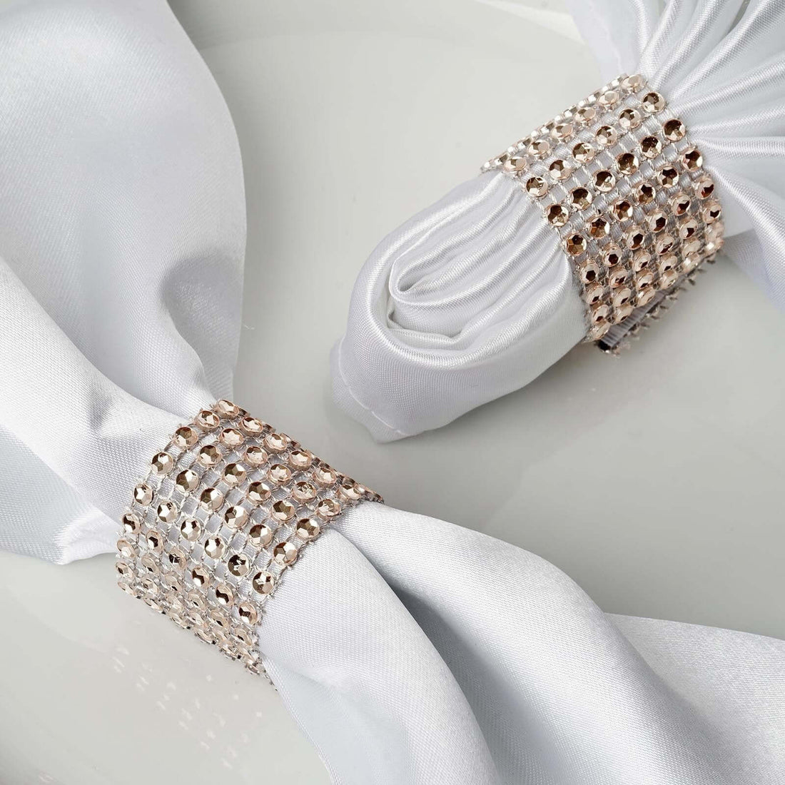 Elegant napkin rings adorned with sparkling crystals on white fabric.