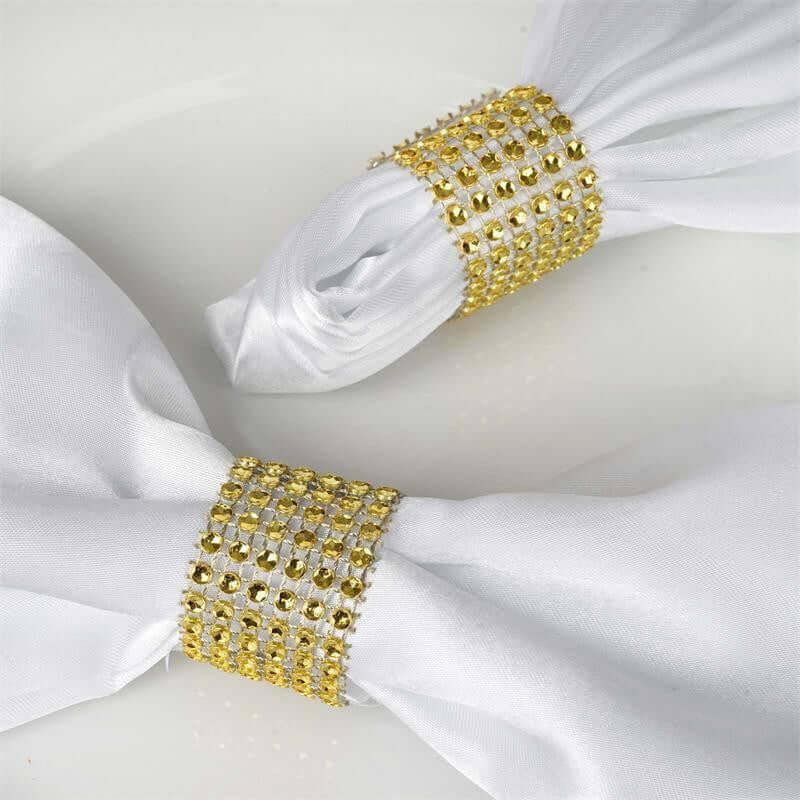 White napkin rings adorned with golden rhinestones.