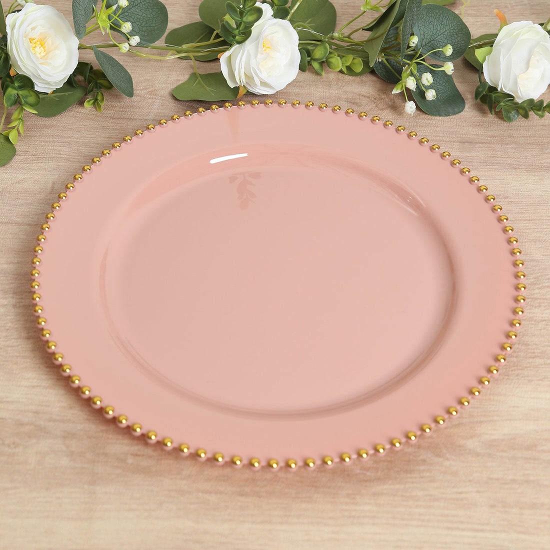 Pink plate with gold beaded edge on a wooden surface.