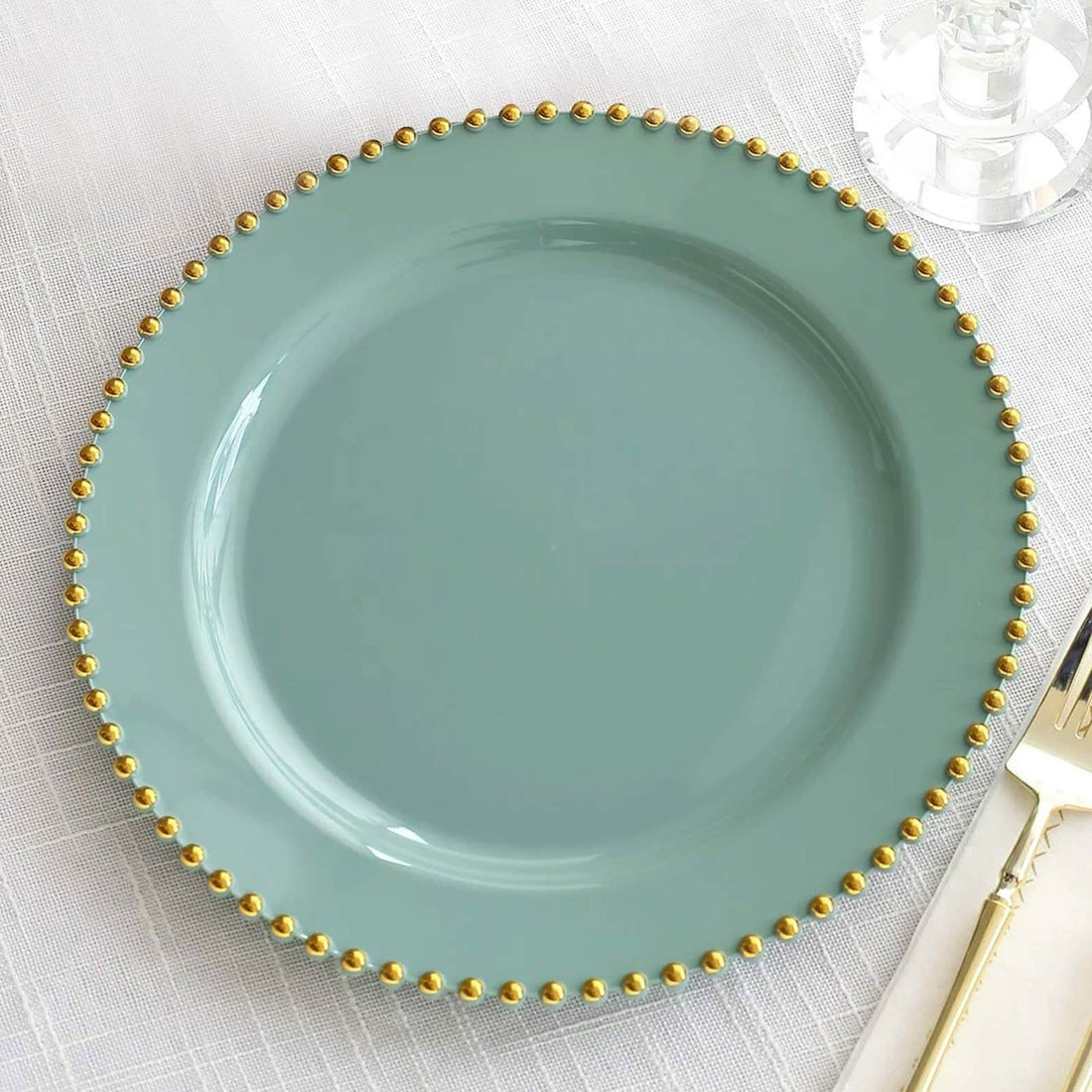Elegant teal plate with gold beaded rim on a textured tablecloth.
