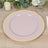 Pink plate with gold rim on a wooden table setting.