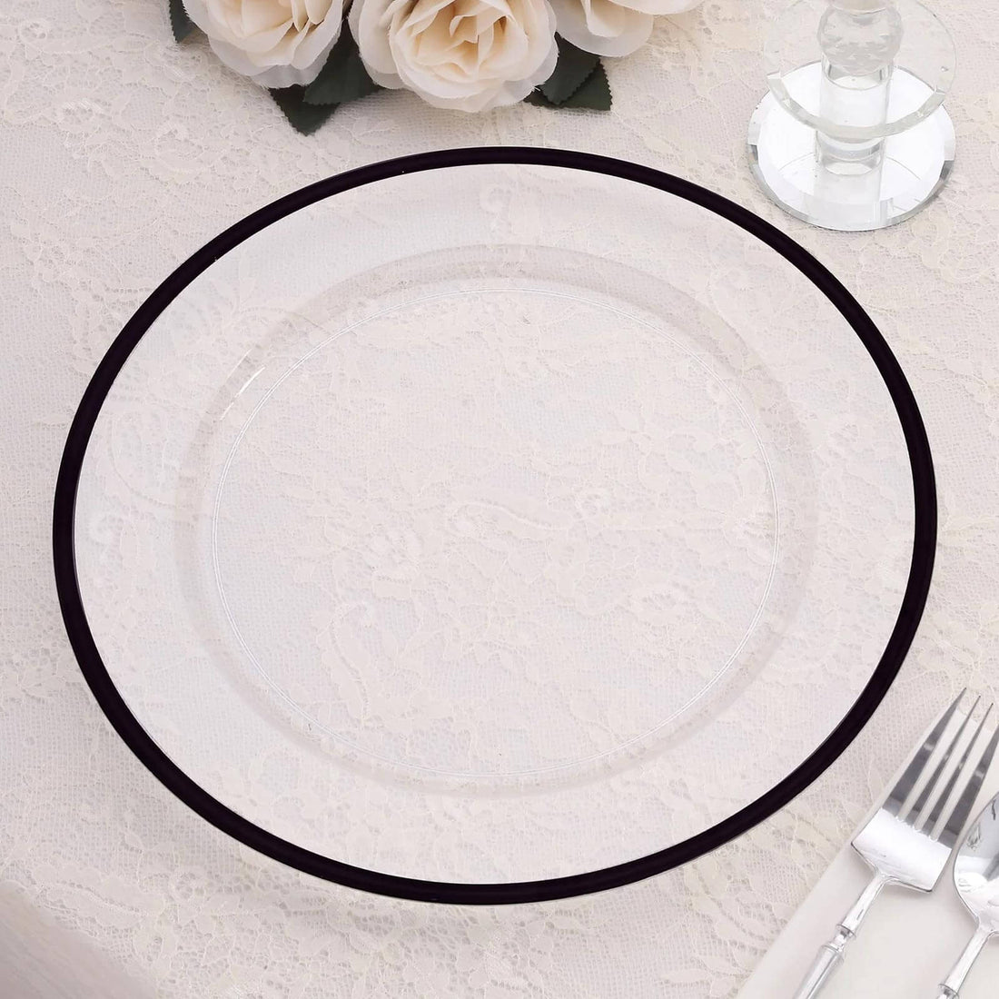 Clear glass plate with black rim on a lace tablecloth.