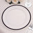 Clear glass plate with black rim on a lace tablecloth.