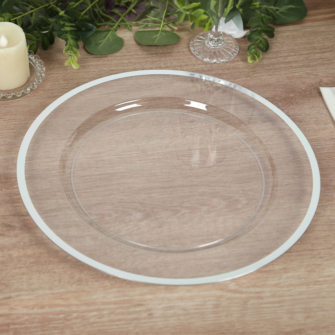 Clear glass charger plate on a wooden table with elegant decor.