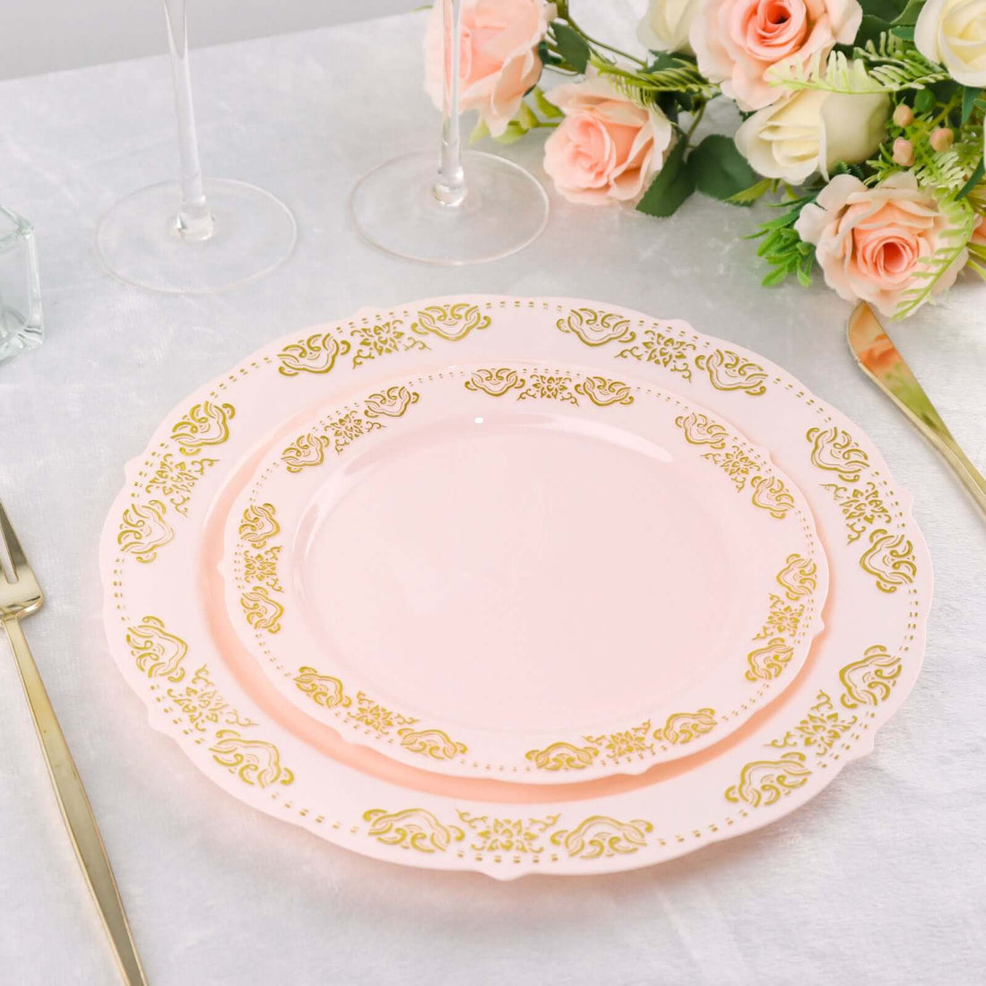 Elegant pink plates with gold floral design on a dining table setting.