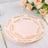 Elegant pink plates with gold floral design on a dining table setting.