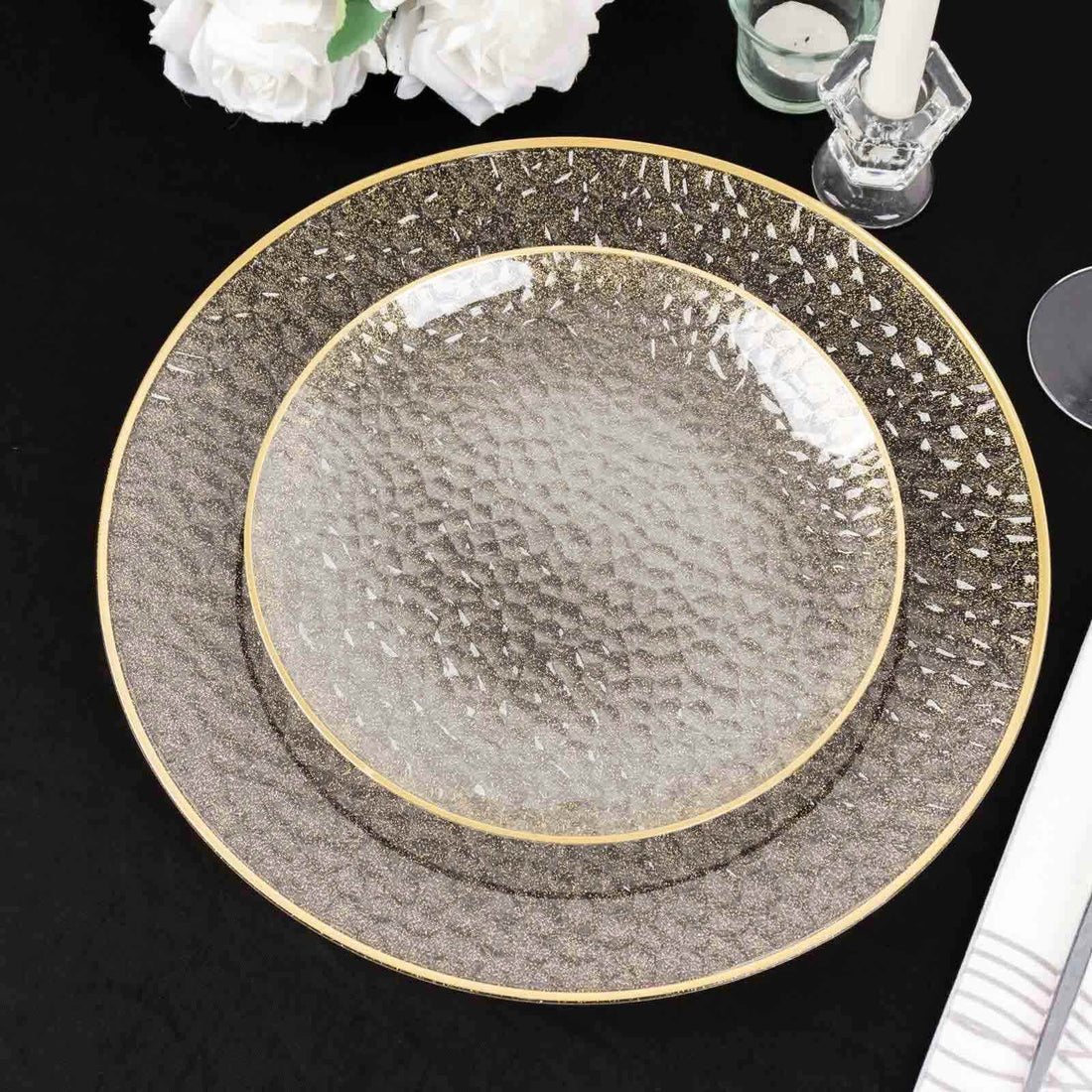 Elegant textured dinner plates with golden rim on a black table setting.
