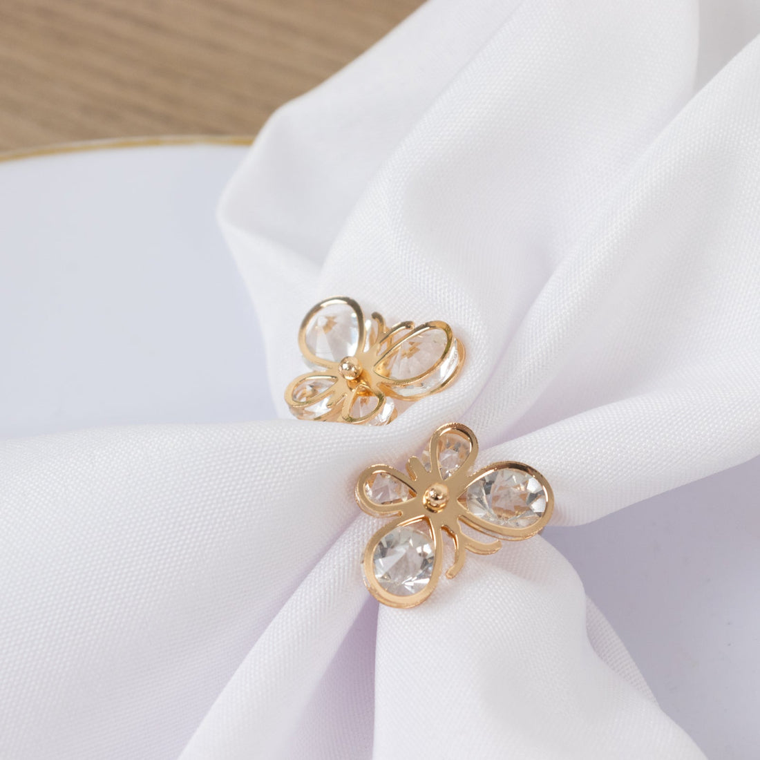 Gold butterfly napkin rings with clear crystals on a white napkin.
