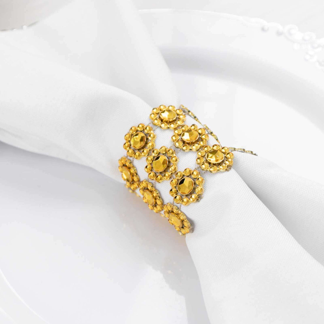 Gold rhinestone napkin ring on a white napkin.