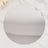 Round mirror on a marble surface, reflecting soft light and floral accents.