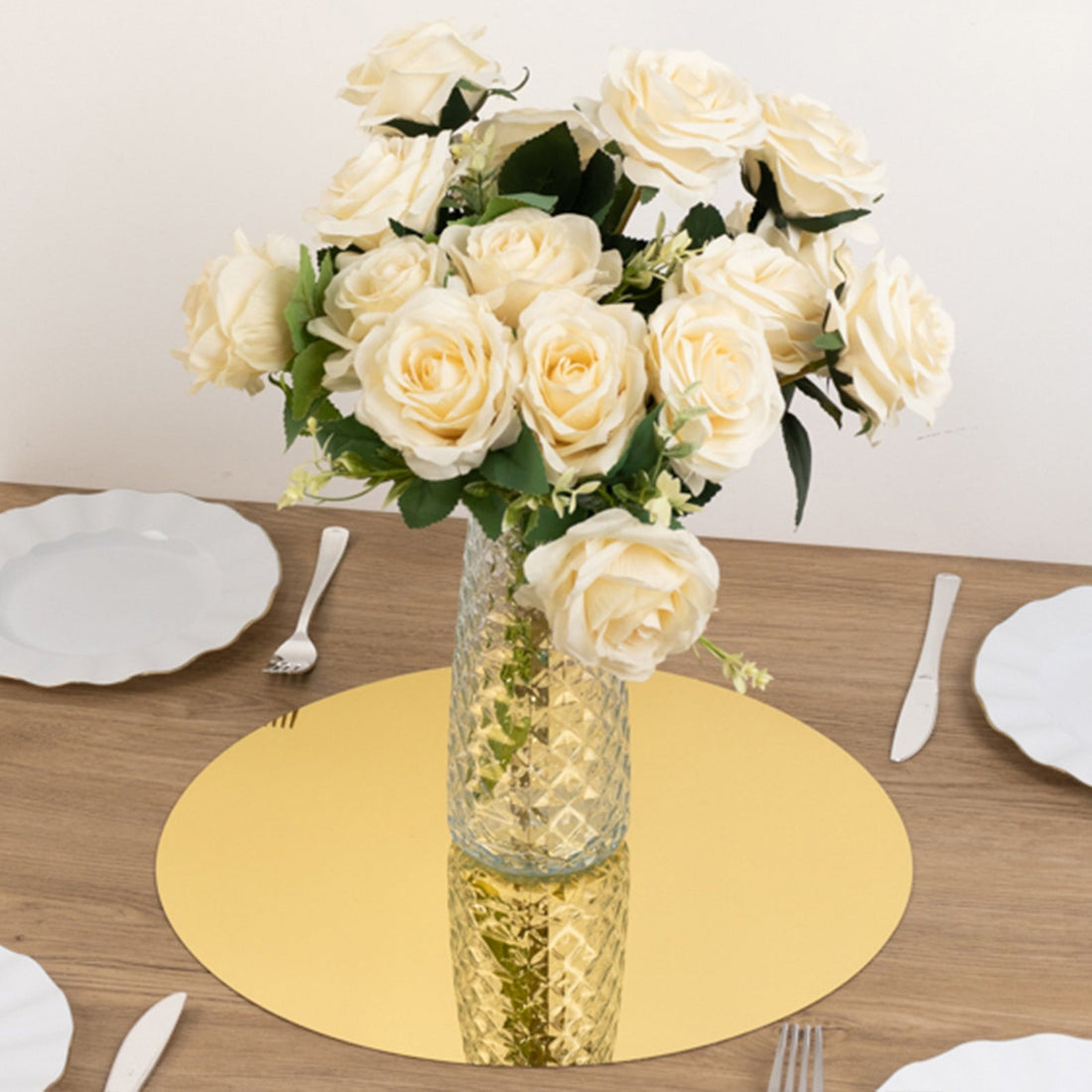 Elegant white roses in a glass vase on a golden mirror base.