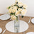 Elegant white roses in a crystal vase on a mirrored table setting.