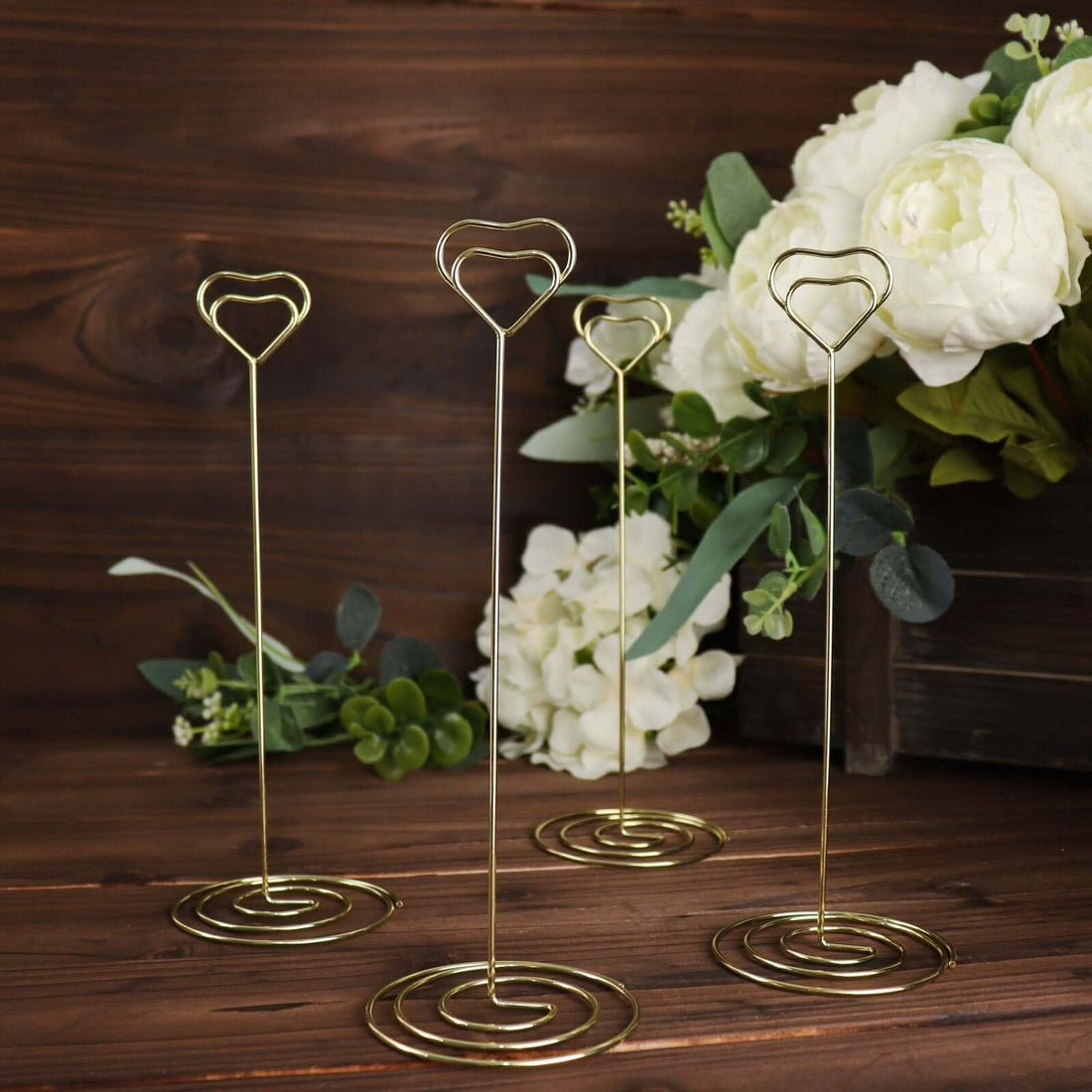 Gold heart-shaped photo holders displayed with floral backdrop.