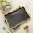 Elegant black and gold decorative serving trays on a table with flowers