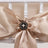 Elegant satin bow with black flower accent and pearl detail on a chair.