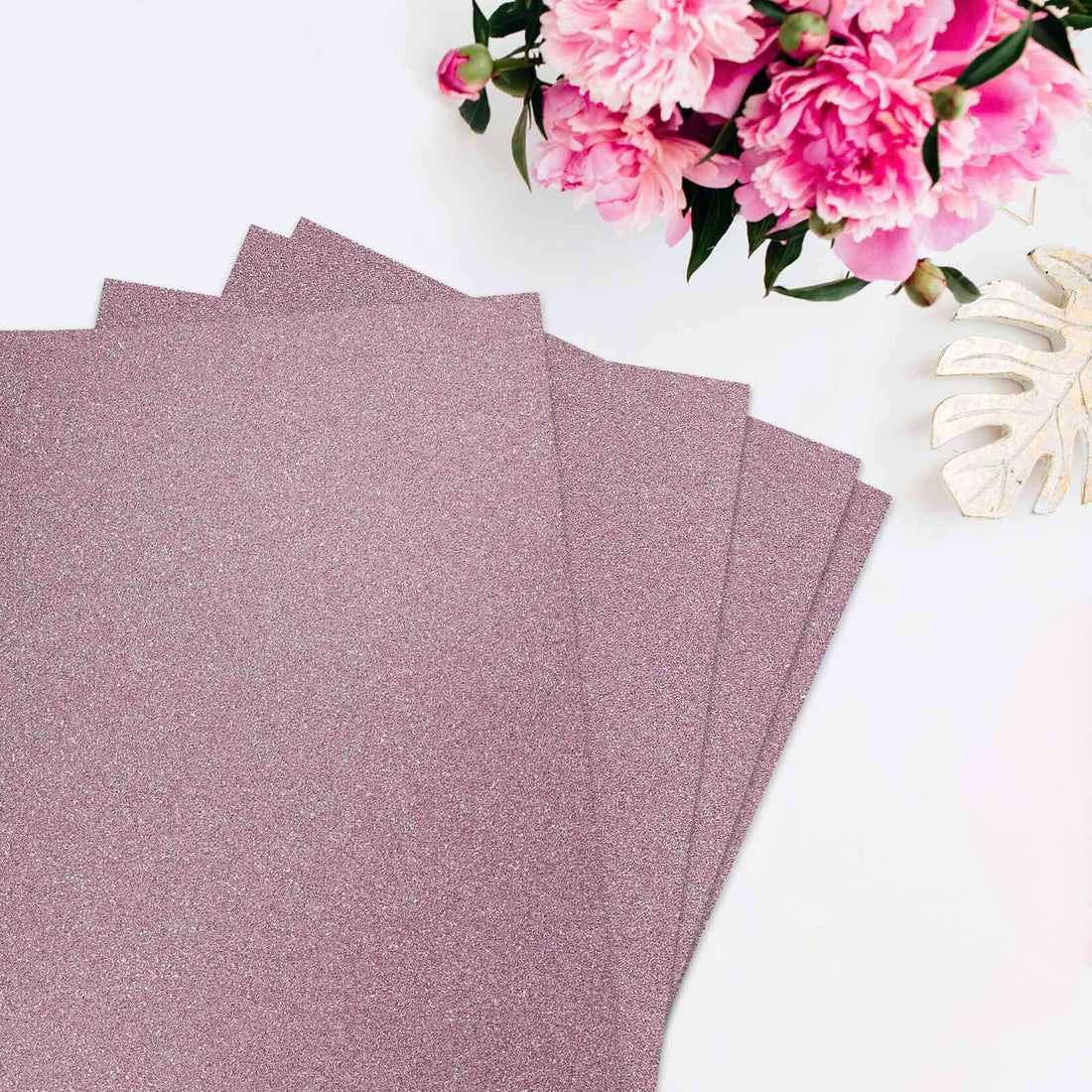 Glitter pink cardstock sheets arranged with pink flowers