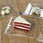 Red velvet cake slice on a clear plate with a flag decoration.