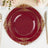 Elegant burgundy plates with intricate gold detailing on a dining table.