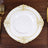 Elegant white plate with gold floral design on wooden table.