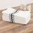 Stack of white kitchen towels with black and green stripes on a wooden table.