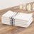 Stack of white kitchen towels with gray stripes on a wooden table.