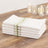 Stack of white kitchen towels with green stripes on a wooden table.