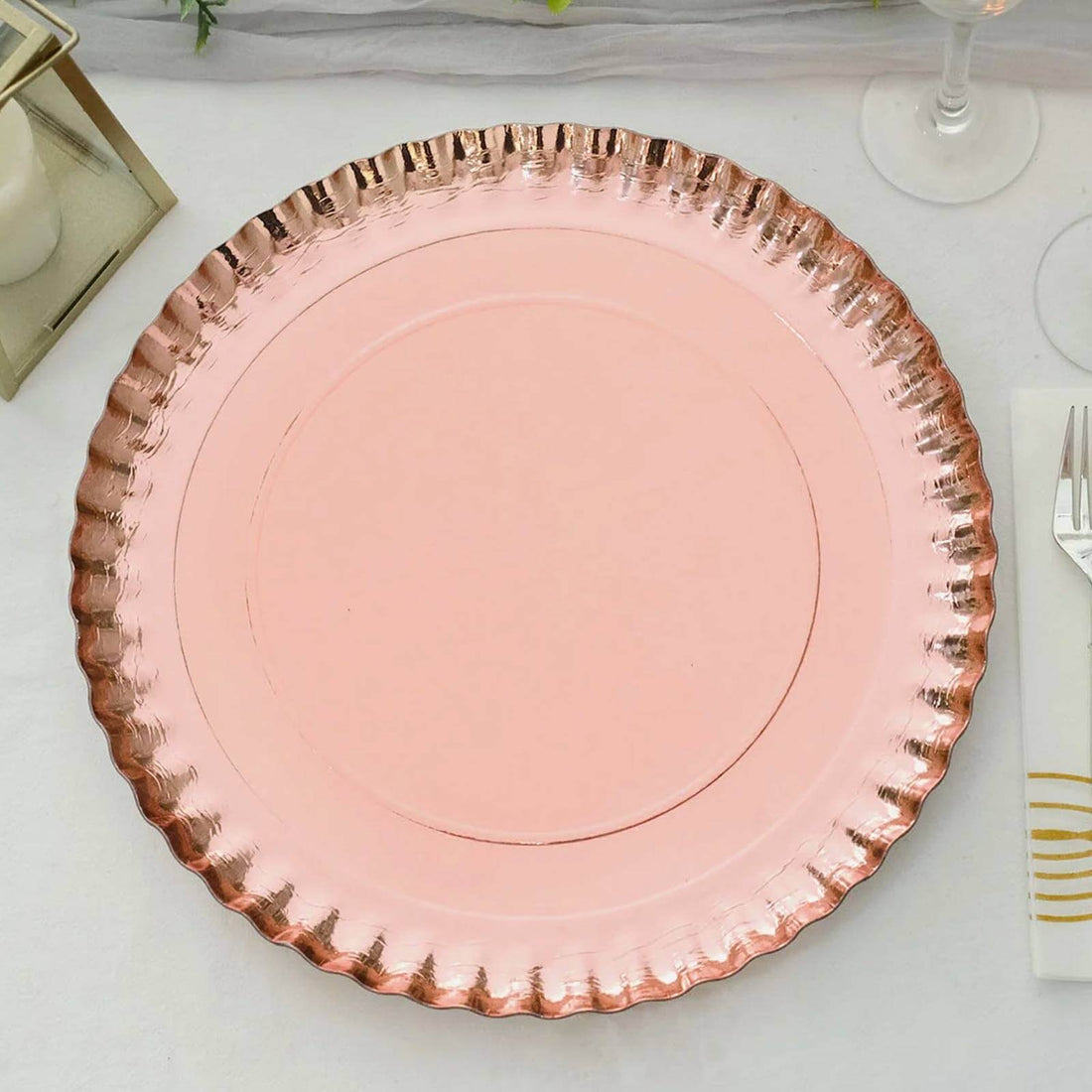Pink charger plate with a decorative rim on a plain background.