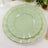 Green scalloped dinner plates stacked on a textured tablecloth.