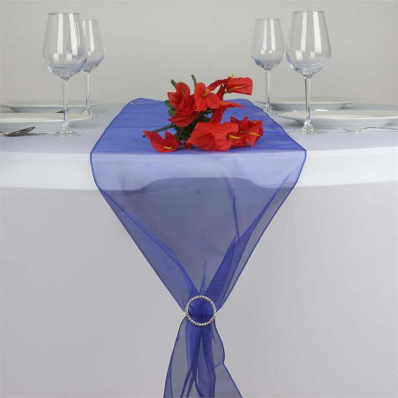 Blue sheer table runner with red floral centerpiece and elegant glassware setup. #whtbkgd
