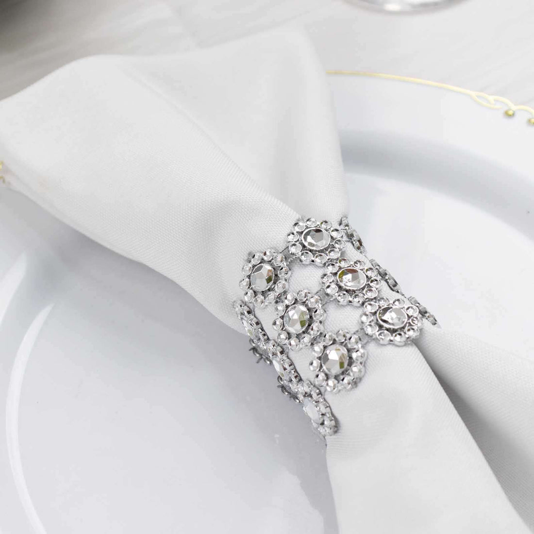 Elegant silver napkin ring adorned with crystals on a white napkin.