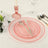Pink glass plates with silver utensils set on a dining table.
