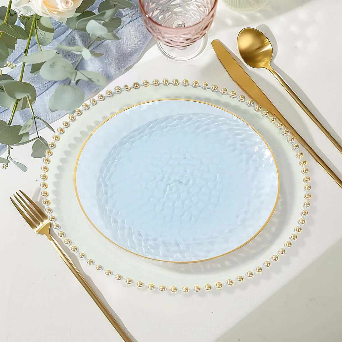 Elegant blue glass plate with gold trim and bead accents on a styled table setting.