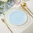 Elegant blue glass plate with gold trim and bead accents on a styled table setting.
