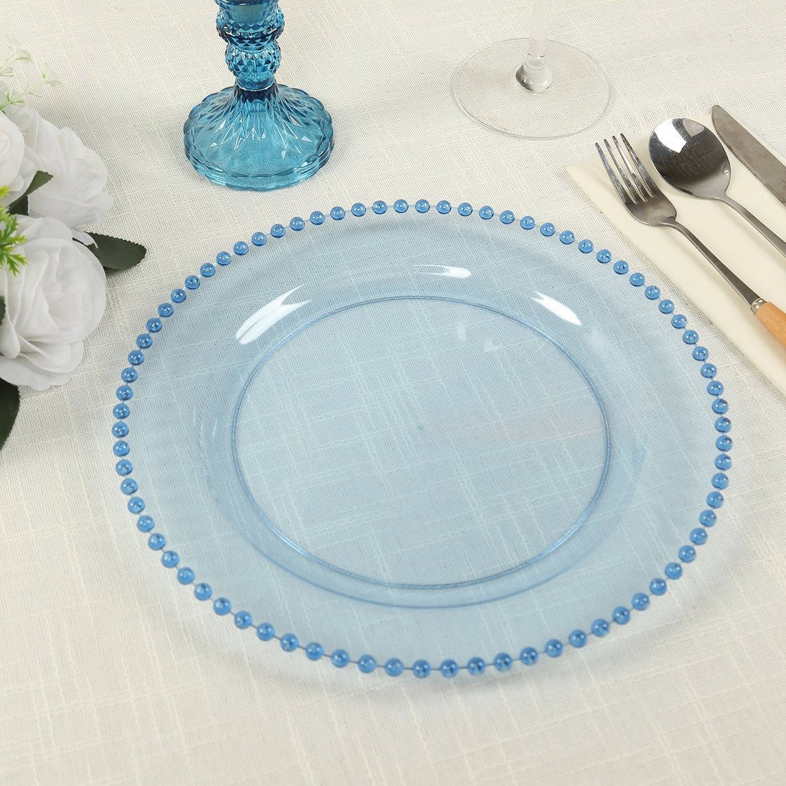 Blue decorative plate with beaded rim on a textured table setting.