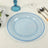 Blue decorative plate with beaded rim on a textured table setting.