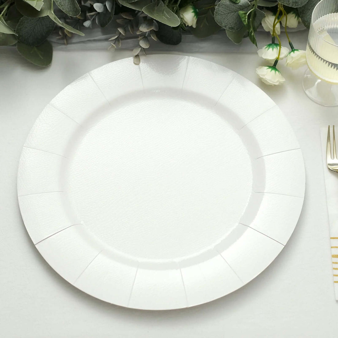 White paper plate on a table with greenery backdrop.