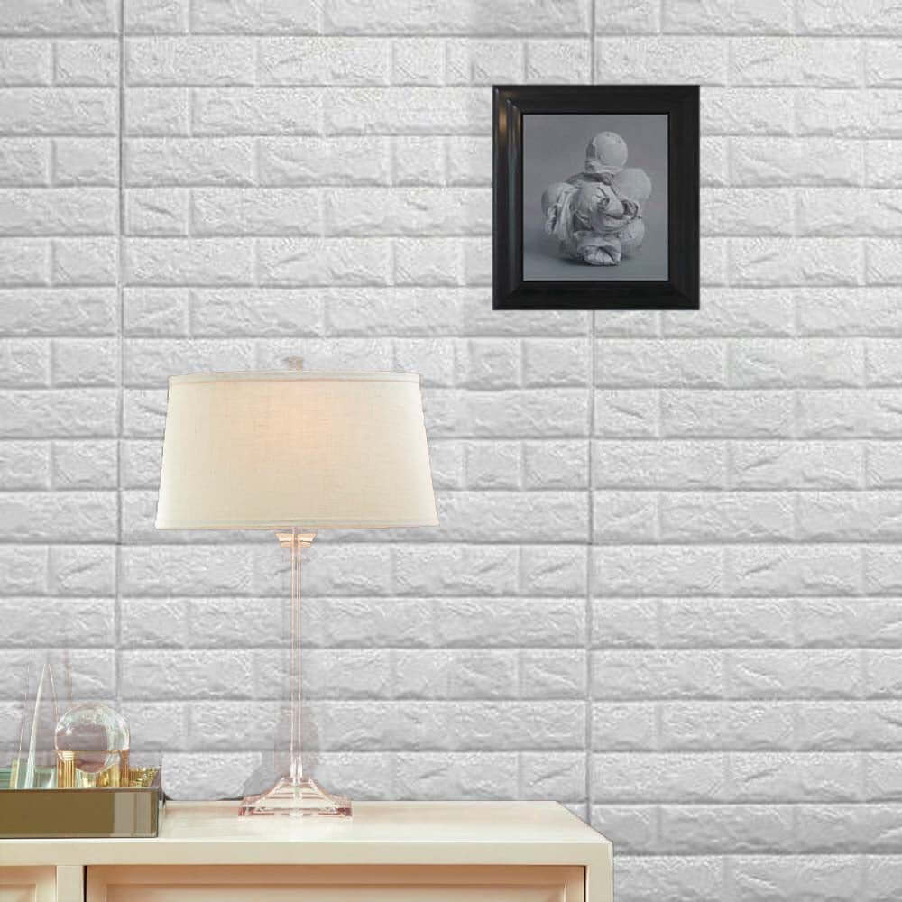 Lamp on a table with a framed photo on a brick wall background.