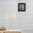 Lamp on a table with a framed photo on a brick wall background.