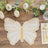 Gold glitter butterfly placemat on a wooden table with flowers and candles.