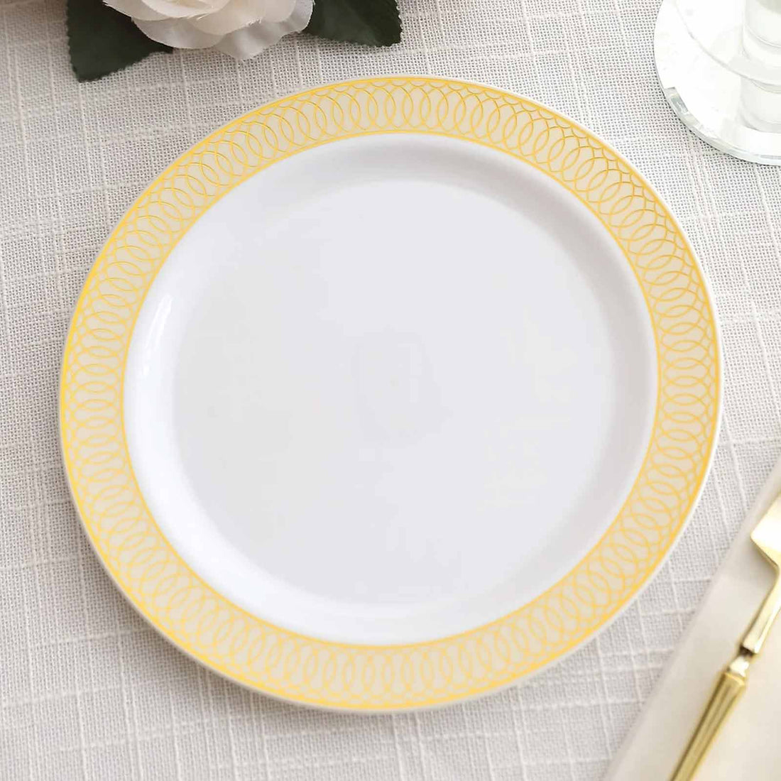 White plate with yellow decorative rim on neutral tablecloth.