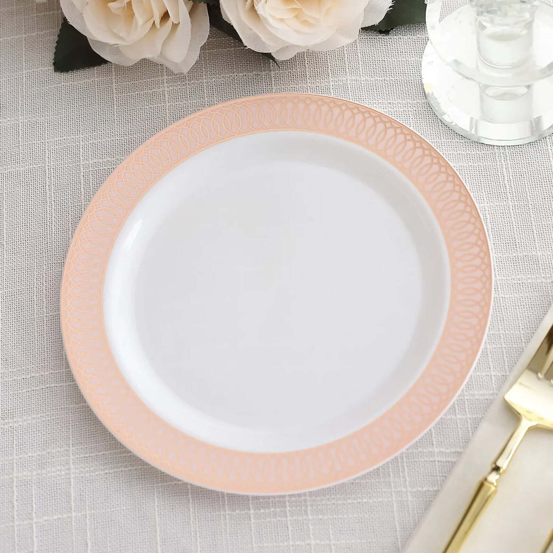 White plate with pink decorative rim on a textured tablecloth.