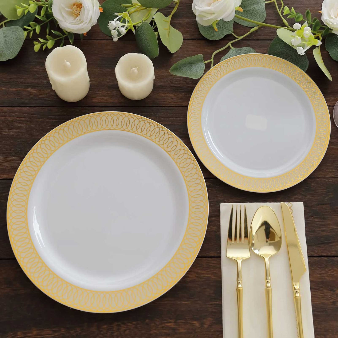 Elegant white plates with gold trim, gold cutlery, and candles on a rustic table setting.