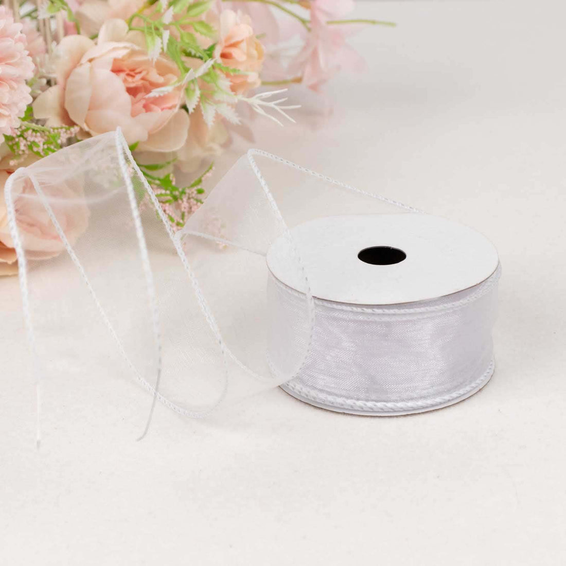 Silver ribbon spool with a flowing ribbon against a light background.