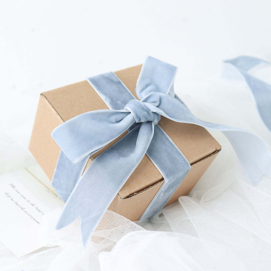 Gift box with blue velvet ribbon on a plain background
